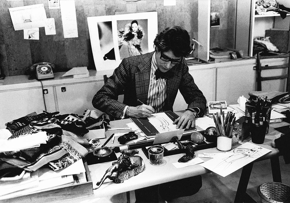 Yves Saint Laurent dessine dans son studio, Paris 1976. © Musée Yves Saint Laurent Paris / Guy Marineau