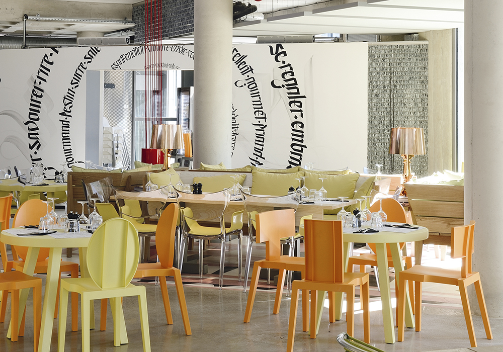 Le restaurant « Les Grands Enfants » agencé par Philippe Starck. Il se situe au rez-de-chaussée de l’immeuble « Le Nuage », à Montpellier, que le designer a également dessiné. Le mobilier coloré est signé TOG, une plateforme internet de personnalisation de meubles.