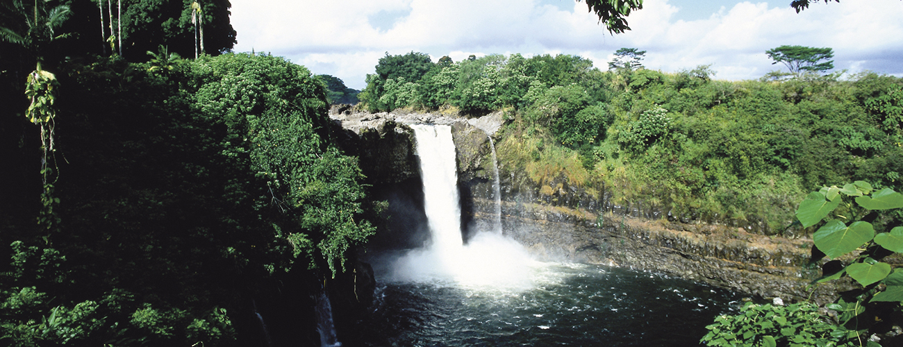 Rainbow Falls à Hawaii. La cascade est enserrée dans la roche et la jungle.