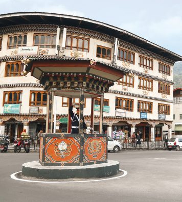 Heure de pointe sur un carrefour de Thimphu. Malgré l’absence d’embouteillages, un agent de la circulation régule le trafic, à l’abri dans une guérite en bois sculpté.