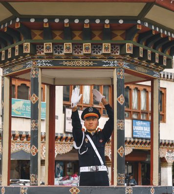 Heure de pointe sur un carrefour de Thimphu. Malgré l’absence d’embouteillages, un agent de la circulation régule le trafic, à l’abri dans une guérite en bois sculpté.