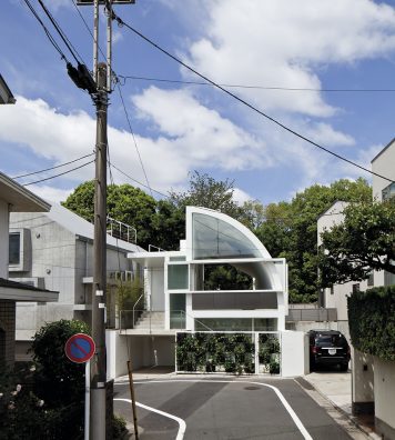 House at Hanegi Park à Tokyo au Japon, 2010. A l’intérieur de la maison, une grande bibliothèque, à droite, est éclairée par une fenêtre qui cadre la verdure. De l’extérieur, la maison semble presque vide, ou en tout cas transparente.